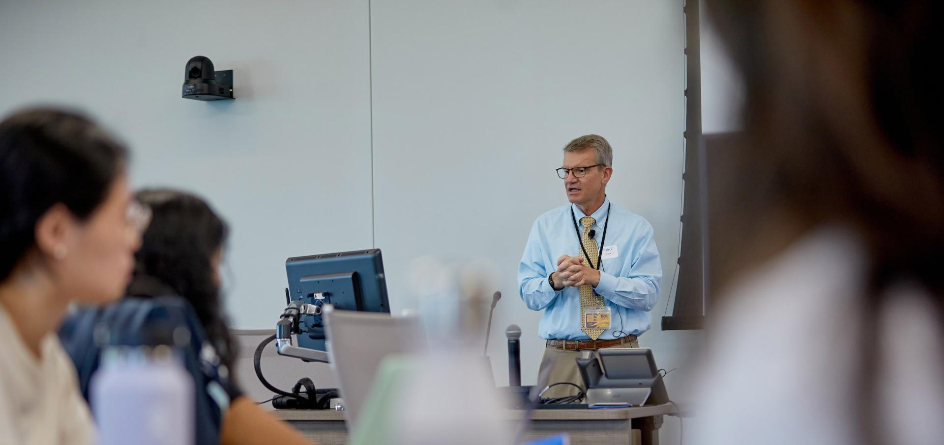 Instructor in white coat teaching students in the classroom