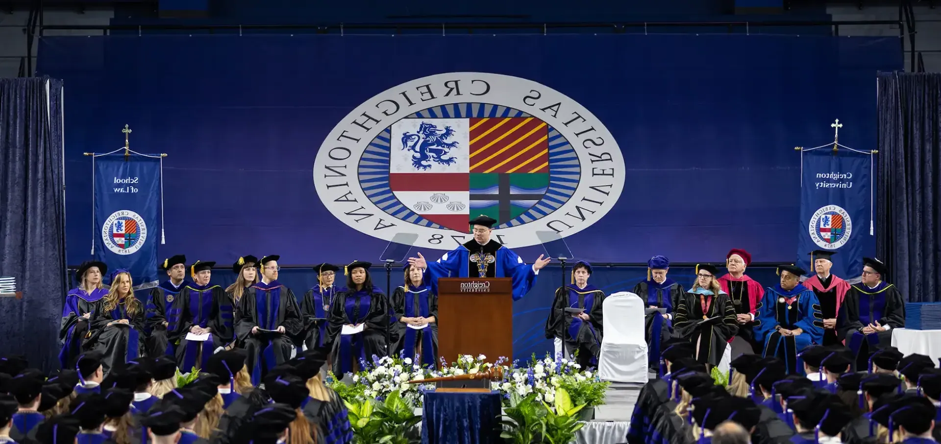 Law commencement with President Father Hendrickson addressing crowd.